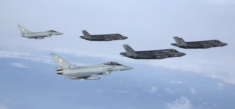 F35 Lightning arrives into the UK, Flanked by 2, 1Sqn Typhoons and photographed by a 100 Sqn Hawk. The first of Britain’s new supersonic ‘stealth’ strike fighters has touched down in the UK for the first time. The F-35B Lightning II jet was flown by RAF pilot Squadron Leader Hugh Nichols on its first transatlantic crossing, accompanied by two United States Marine Corps F-35B aircraft from their training base at Beaufort, South Carolina. The combined US/UK team of aircrew and engineers are here in the UK to demonstrate just what the 5th generation state of the art aircraft can do, flying at the Royal International Air Tattoo and Farnborough International Air Show over the next few weeks. The aircraft are due to enter service with the Royal Navy and RAF from 2018.